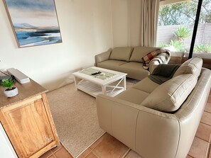 A living room with a sofa, a coffee table, a small cabinet, and a painting on the wall.
