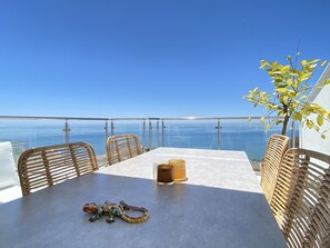 A balcony with a table, chairs, and a glass of beverage. - Duplex in Nerja With Stunning Sea Views (Nerja)