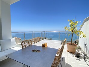 A balcony with a table, chairs, a sofa, and a potted plant. - Duplex in Nerja With Stunning Sea Views (Nerja)
