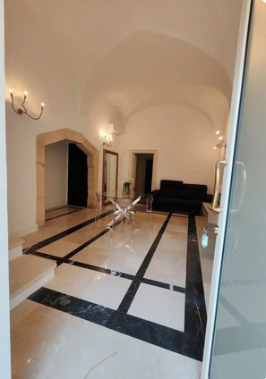 A spacious living area with a glass coffee table, a black sofa, and a marble floor. - Charming Lodge Retreat in the Heart of Provincia di Lecce (Provincia di Lecce)