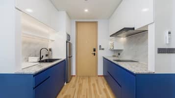 A modern kitchen with blue cabinets, a stainless steel refrigerator, and a wooden door.