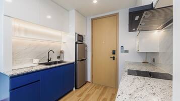 Una cocina moderna con microondas integrado, refrigerador de acero inoxidable y puerta de madera.