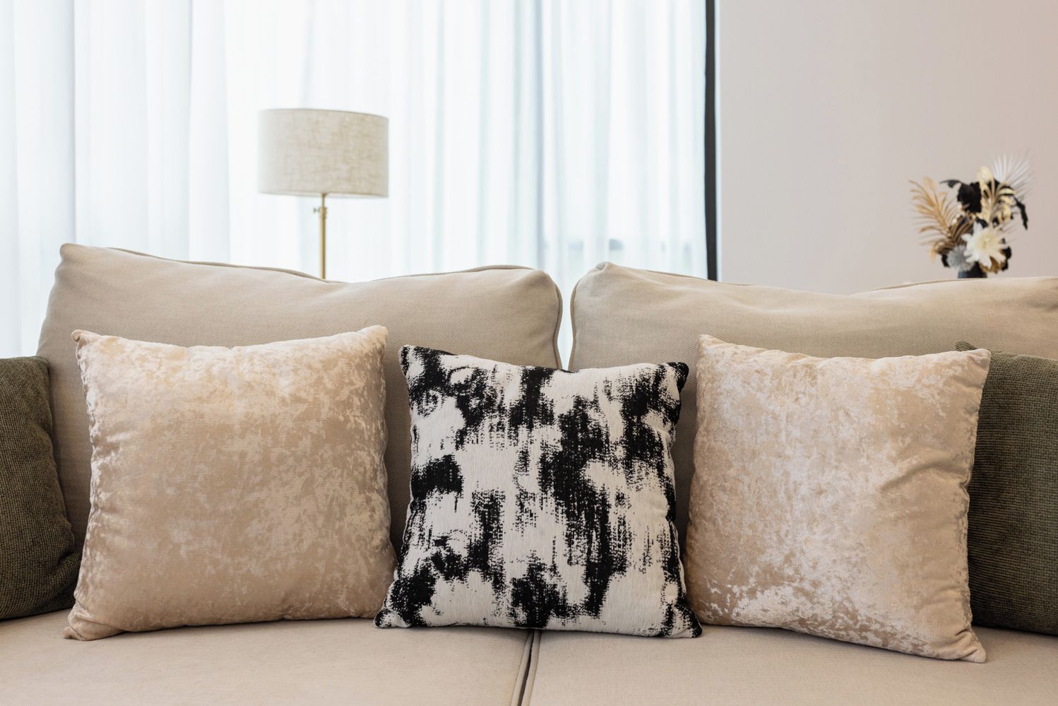 A sofa with three cushions in a living room.