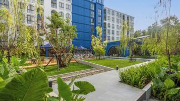 A hotel courtyard with a pool, lounge chairs, and a variety of plants.
