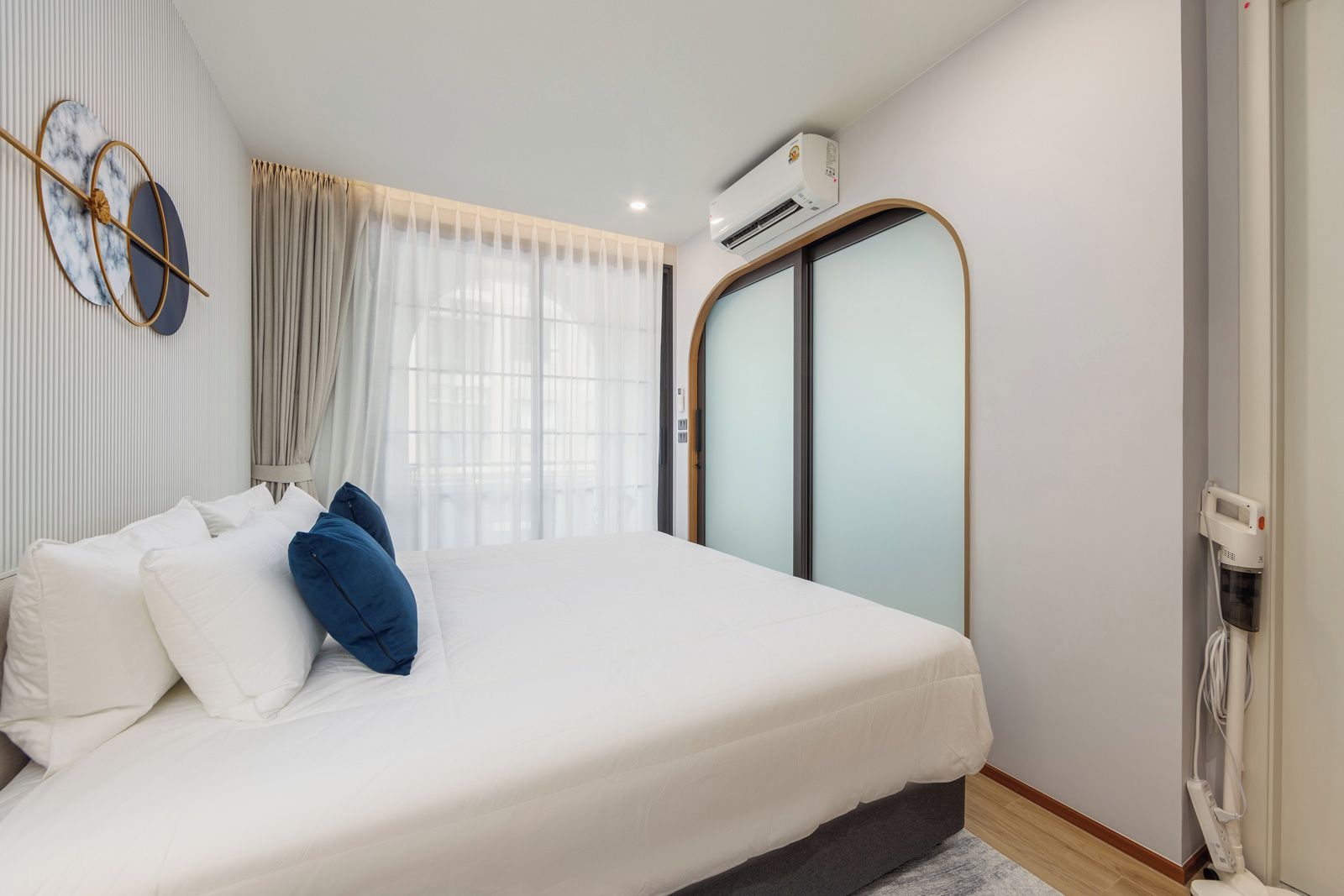 A modern bedroom with a bed, curtains, an air conditioning unit, and a wall-mounted phone.