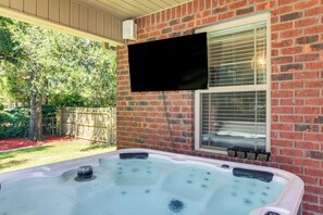 Ein Whirlpool mit Düsen, ein an der Wand montierter Fernseher und eine Ziegelhausfassade.