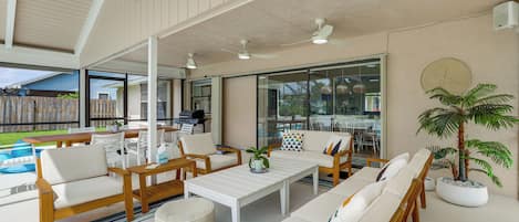 An open-plan living area with a pool view, outdoor seating, and ceiling fans.