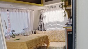 A cozy interior with a dining area featuring a table and two cushioned seating areas. - Romantic Clarens Getaway - Glamped Caravan with Braai & Fairy Bath (Clarens)