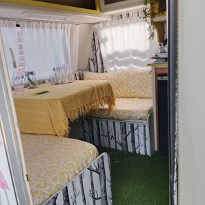 Un intérieur chaleureux avec un coin repas comprenant une table et deux espaces de détente avec des sièges confortables.