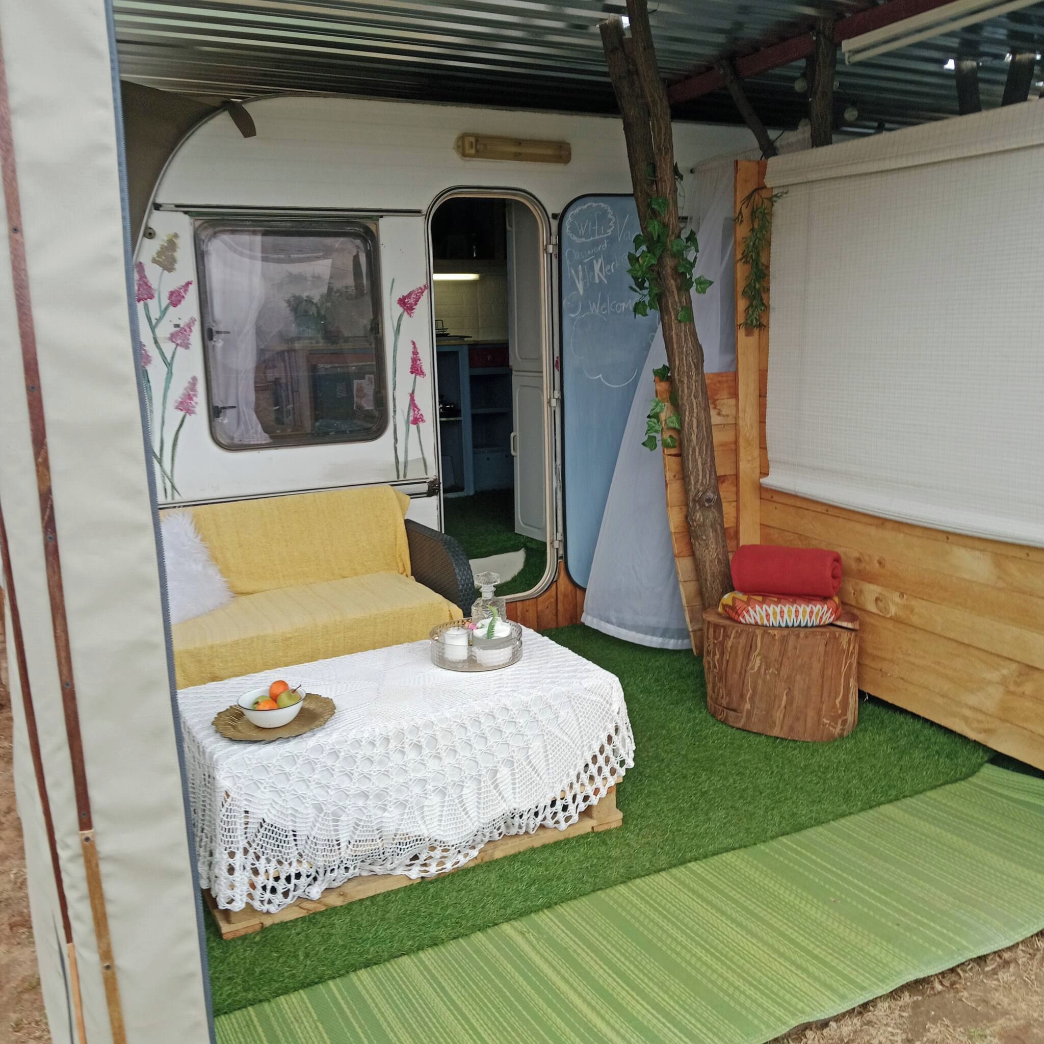 Un intérieur chaleureux avec un lit, une petite table sur laquelle se trouve un bol de fruits et un banc en bois.