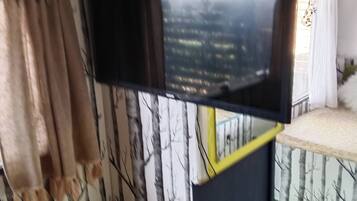Ein Zimmer mit einem Bett, einem Vorhangfenster und einer Wand mit einem Baummuster.