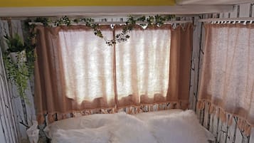 A bed with white bedding, a nightstand with a lamp, and a wall with a tree pattern.