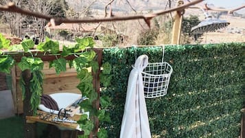A garden with a wooden pergola, climbing plants, a white chair, and a metal basket.
