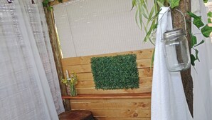A bathroom with a wooden vanity, a mirror, a green artificial grass wall, a hanging lantern, and a small plant on the vanity. - Romantic Clarens Getaway - Glamped Caravan with Braai & Fairy Bath (Clarens)