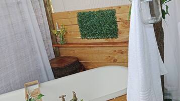 Une salle de bain avec un meuble-lavabo en bois, un miroir, un mur recouvert de gazon artificiel vert, une lanterne suspendue et une petite plante posée sur le meuble-lavabo.