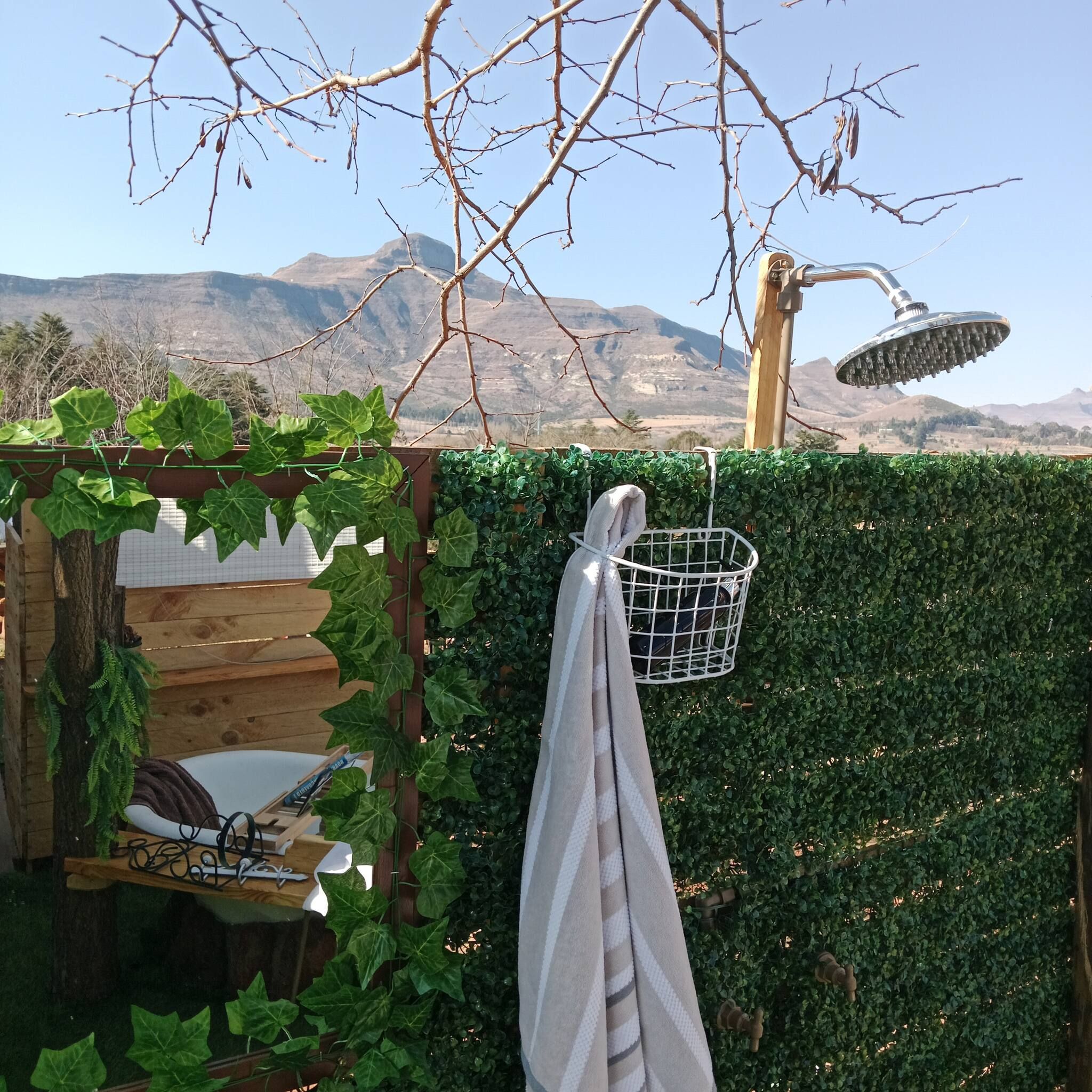 A wooden deck with a metal chair, a white towel hanging on a metal rack, and a metal showerhead.