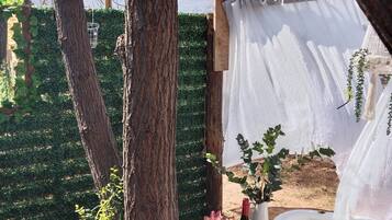 Een rustieke buitenomgeving met een gedekte tafel voor een maaltijd, omringd door bomen en een wijngaard op de achtergrond.