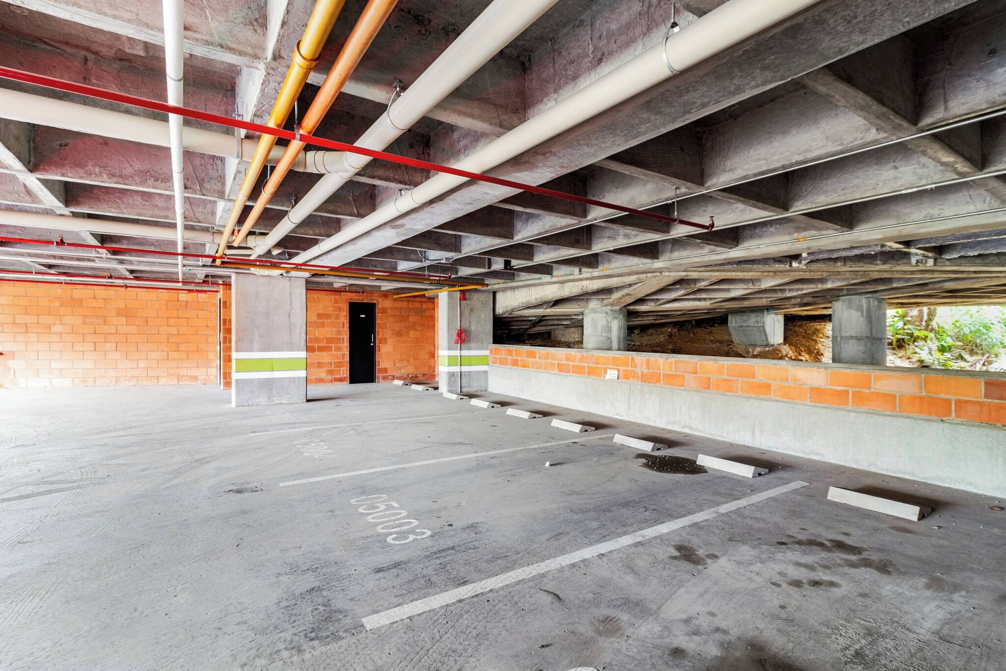 Eine Tiefgarage mit Betonböden, Backsteinwänden und freiliegenden Stahlträgern.