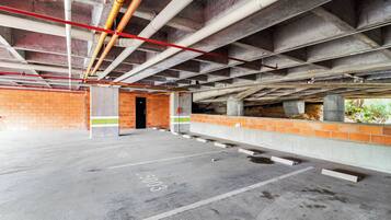 Eine Tiefgarage mit Betonböden, Backsteinwänden und freiliegenden Stahlträgern.