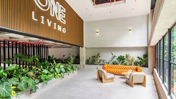 Un intérieur moderne avec un mur en bois sur lequel est inscrit « ONE LIVING », et un espace salon comprenant un canapé et des fauteuils.