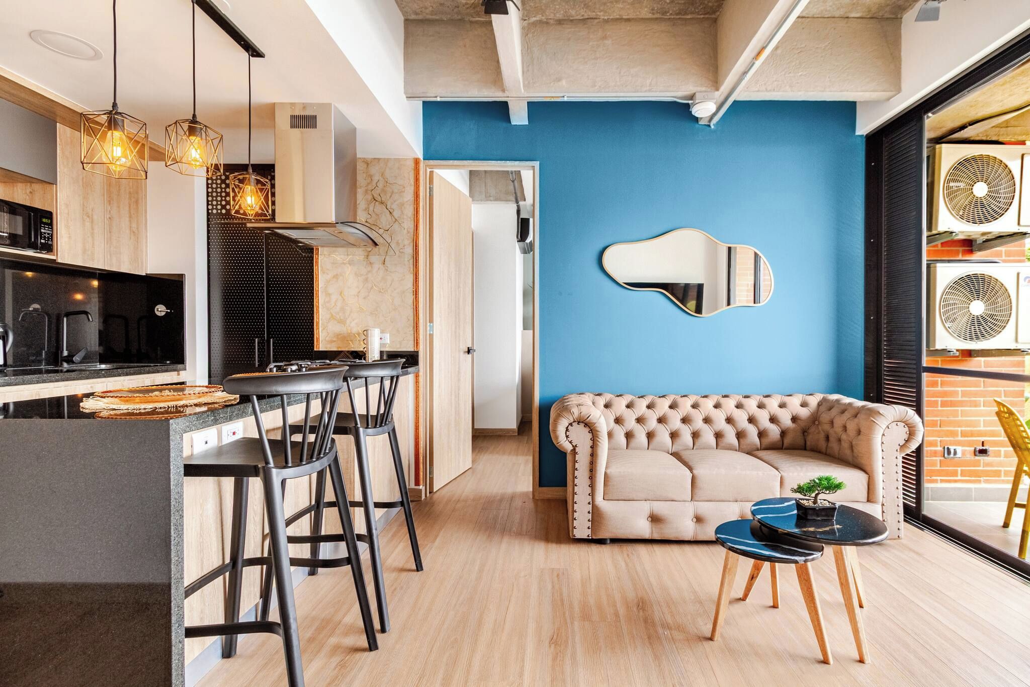 Een moderne keuken met een bar, een blauwe accentmuur en een gestoffeerde bank in een woonruimte.