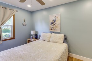 A bedroom with a bed, a nightstand, a lamp, a ceiling fan, and a window with curtains. - Lakefront Adirondack Escape! Fire Pit & Game Room (Broadalbin)