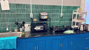 Een keuken met een blauw aanrecht, een rijstkoker, een broodrooster en een waterkoker.