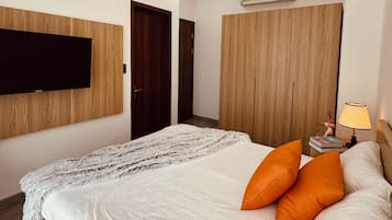 Une chambre moderne avec un grand lit, un téléviseur fixé au mur, une armoire et un appareil de climatisation.