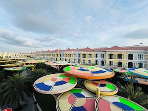 Une cour intérieure agrémentée de plusieurs parasols colorés, avec un bâtiment aux fenêtres en arc de cercle en arrière-plan.