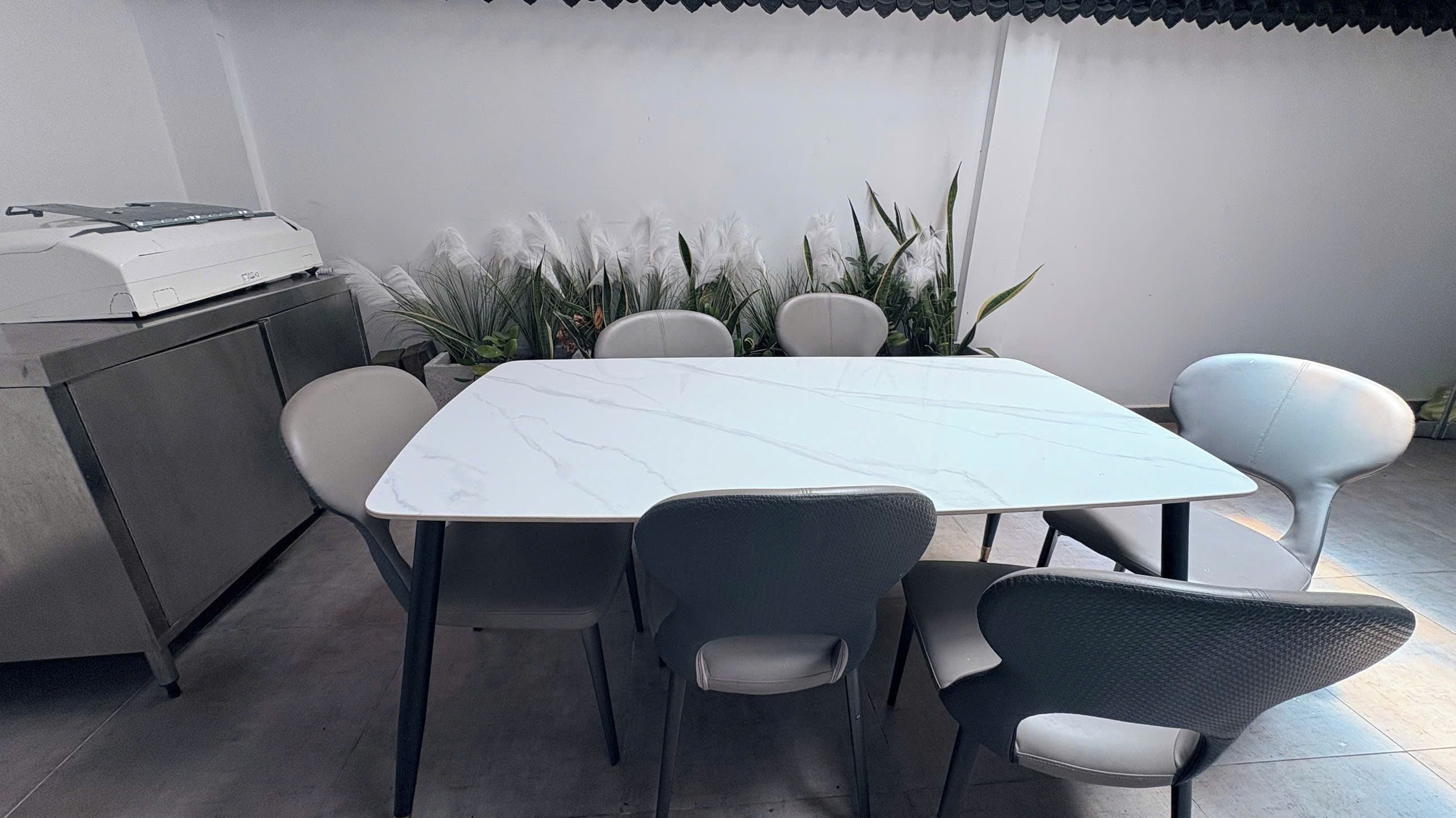 Un coin repas avec une table blanche, quatre chaises et un barbecue.