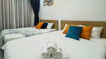 Ein Hotelzimmer mit zwei Betten, einem großen Fenster mit Vorhängen und Bildern an den Wänden.