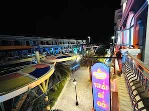 A nighttime view of a hotel with a brightly lit sign, a curved pathway, and a building with arched windows. - Teddy Pumpkin – Grandworld Phu Quoc – Near beach (Phu Quoc)