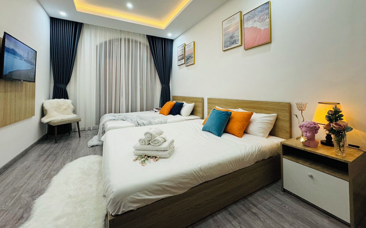 A hotel room with a large bed, a chair, a TV, and a nightstand with a lamp.