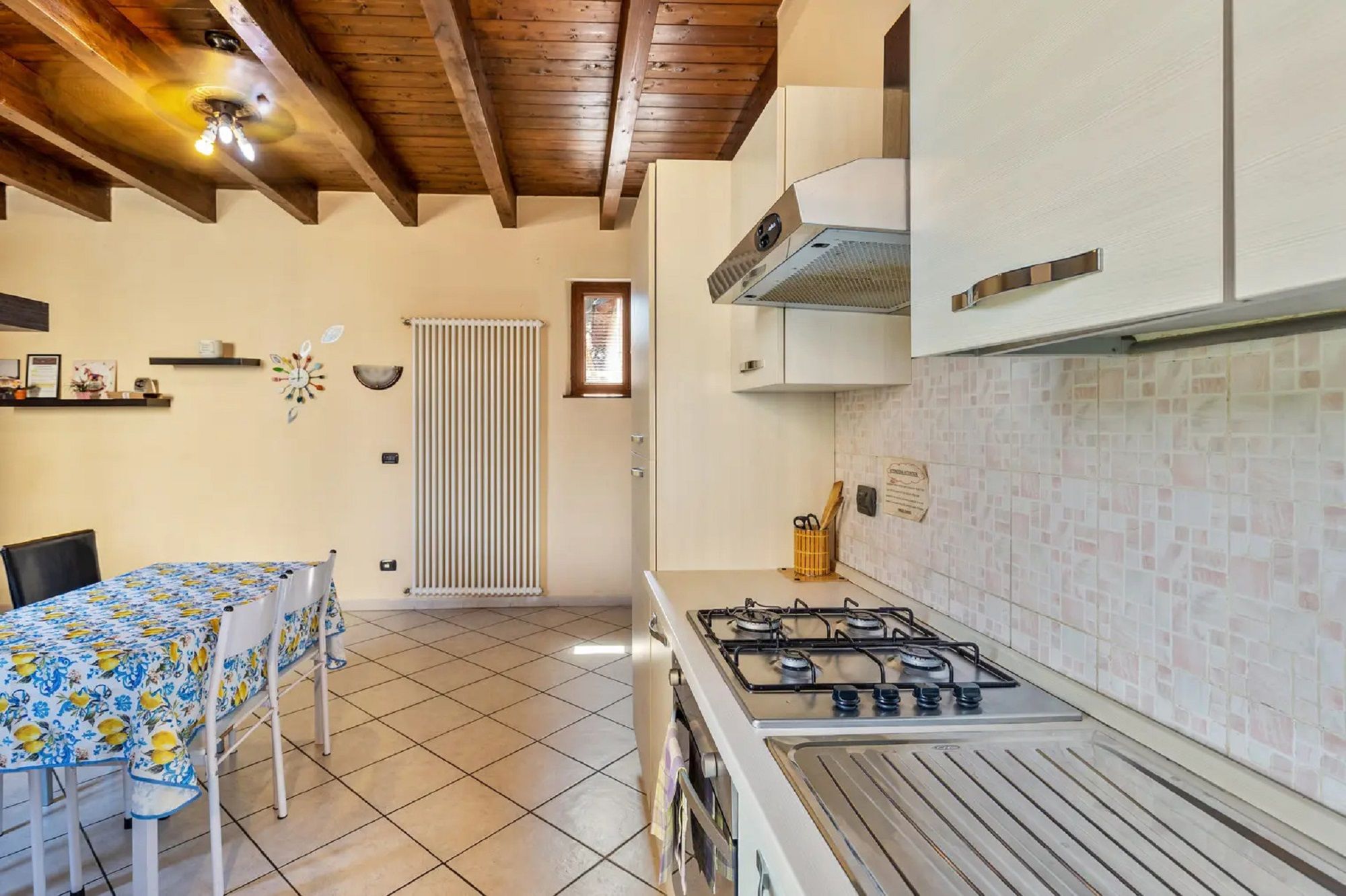 A kitchen with a gas stove, white cabinets, a tiled backsplash, and a wooden ceiling.