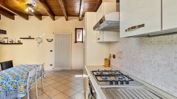 A kitchen with a gas stove, white cabinets, a tiled backsplash, and a wooden ceiling.