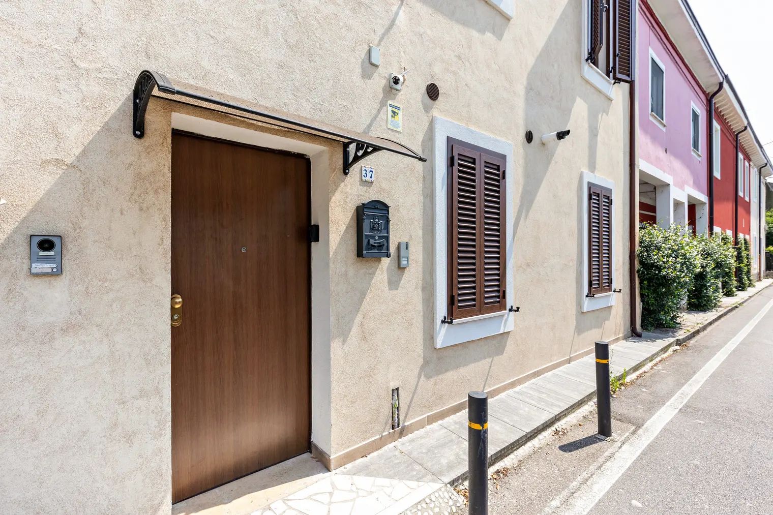 A building with a large wooden door, a mailbox, and a number plate.