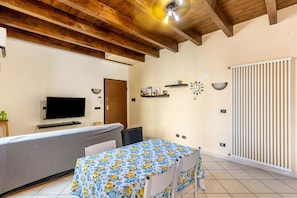 A room with a bed, a table with a tablecloth, a television, a door, and a radiator. - house verona (Veneto)