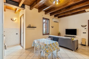 A cozy living area with a sofa, a TV, and a table with chairs. - house verona (Veneto)