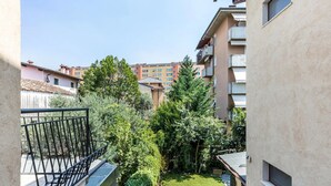 Un cortile con un piccolo prato, una ringhiera in metallo e vista sugli edifici circostanti.
