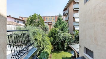 A courtyard with a small lawn, a metal railing, and a view of surrounding buildings.