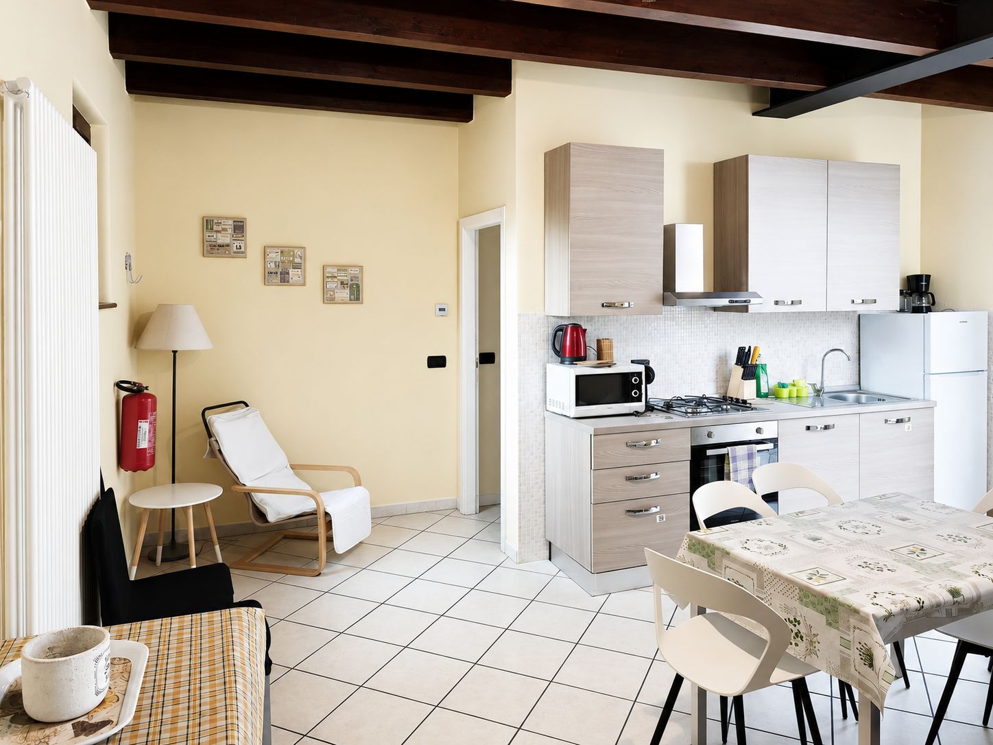 Cocina compacta con microondas, estufa y lavabo, junto a un comedor con mesa y sillas.