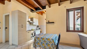 Una cucina compatta con elettrodomestici moderni, un tavolo da pranzo con tovaglia a fiori e una finestra vista.