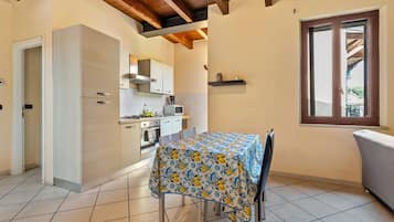 A compact kitchen with modern appliances, a dining table with a floral tablecloth, and a window with a view.