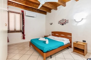 Un dormitorio con una cama de madera, una mesita de noche, una ventana con persianas y un ventilador de techo.