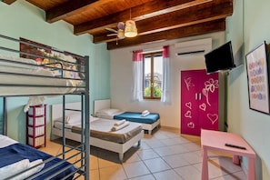 Una habitación con literas, televisión, escritorio y ventana con cortinas.