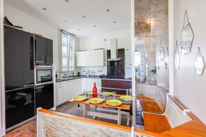 Une cuisine moderne avec un coin repas, des meubles blancs et un pare-feu en marbre.