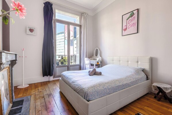 A bedroom with a bed, a dresser, a vanity, a window with curtains, and a framed picture on the wall. - The best view of the Eiffel Tower (Paris)