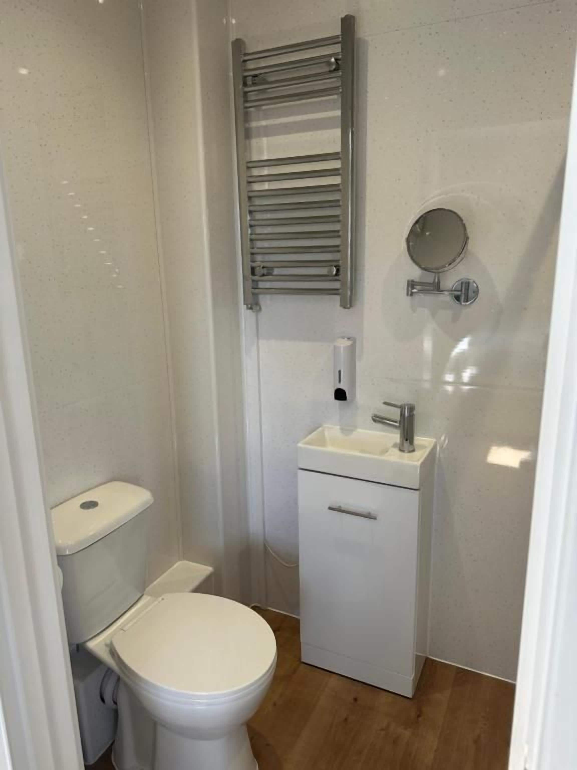 A small, compact bathroom with a toilet, sink, and a towel rack.