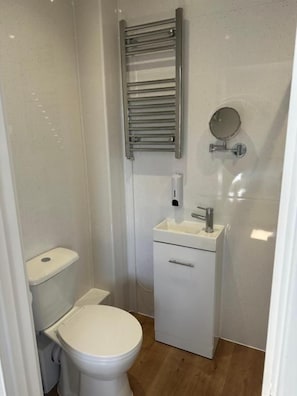 A small, compact bathroom with a toilet, sink, and a towel rack.