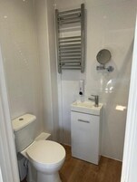 A small, compact bathroom with a toilet, sink, and a towel rack.